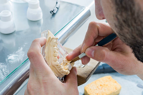 istock Dental technician applying ceramics to teeth in the dental model 511055370