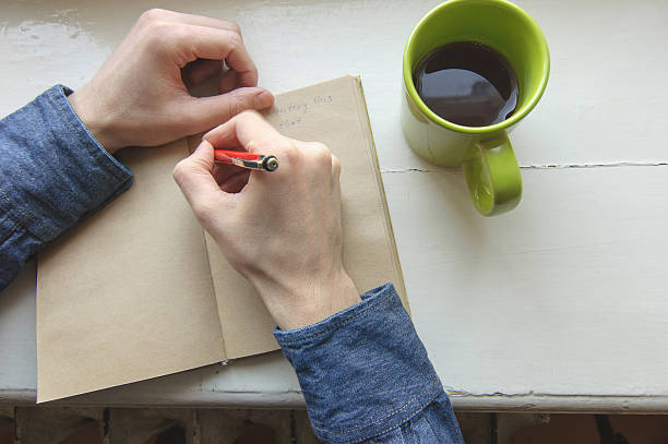 istock male right hand writing on notebook in morning time 511059592