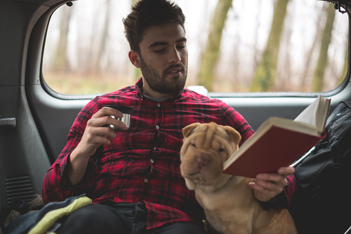 Man reading a book and spending time with his dog.