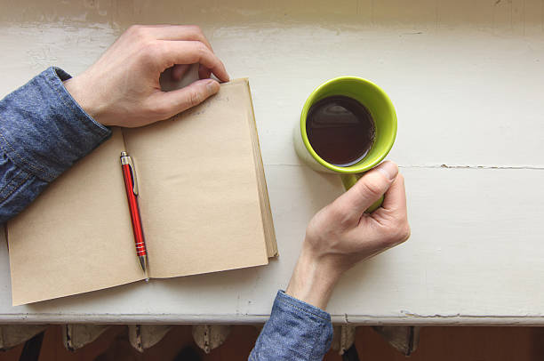istock Male right hand holding cup with writing on notebook 511059722