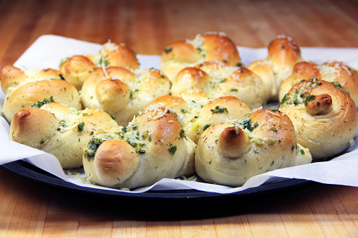 A tray of freshly baked garlic knots on parchment paper