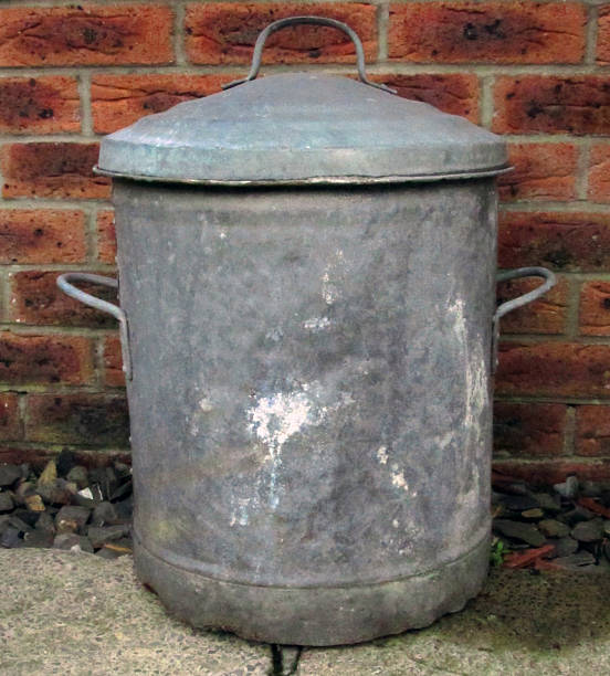 istock Metal battered dustbin against a red brick wall 511060395