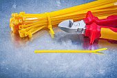 Cutting pliers yellow cable ties on metallic background construc