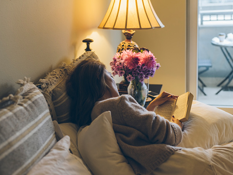 Japanese woman reading at home, Seattle,WA, USA.