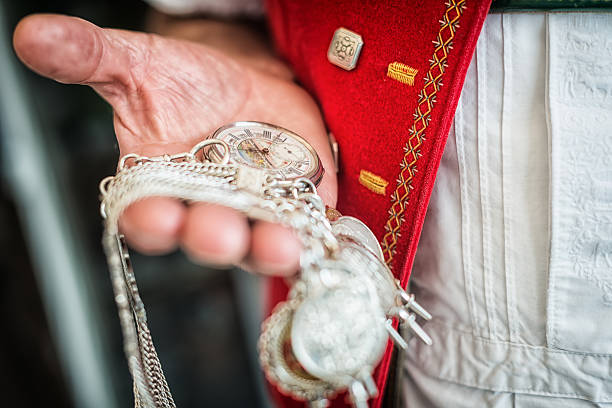 farmer in traditional swiss costume checks time on pocket watch Appenzell, Switzerland - Mars 29, 2014: Man's hand holding pocket watch to check time. He's wearing a traditional swiss clothing which is used especially in the canton of Appenzell. appenzell stock pictures, royalty-free photos & images