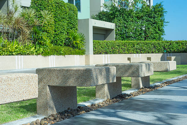 A weathered stone bench nestled in a vibrant green garden. This peaceful setting invites relaxation under dappled sunlight, perfect for enjoying nature.