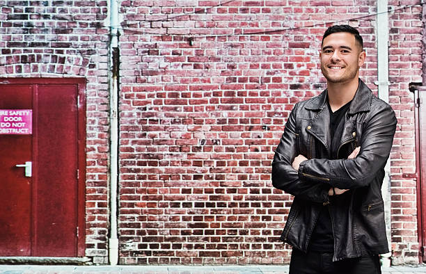 istock Smiling casual man standing in front of brick wall 511071966