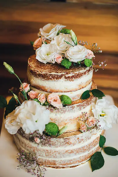Wedding cake with roses whipped cream on a wooden background