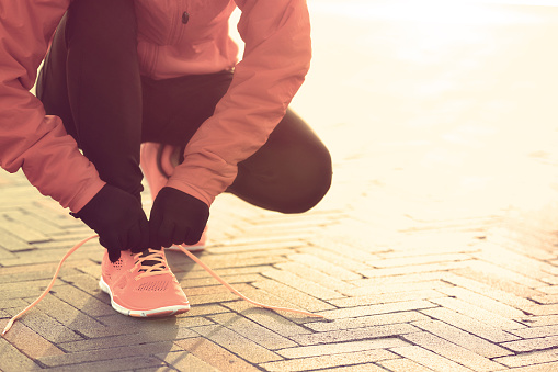 young sports woman runner tying shoelace at sunrise