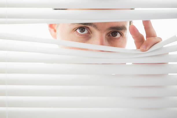 istock Suspicious male eyes spying through roller blind 511092077