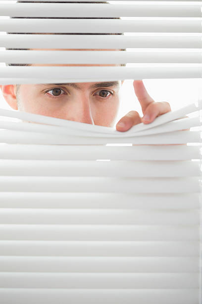 istock Serious male eyes spying through roller blind 511092949