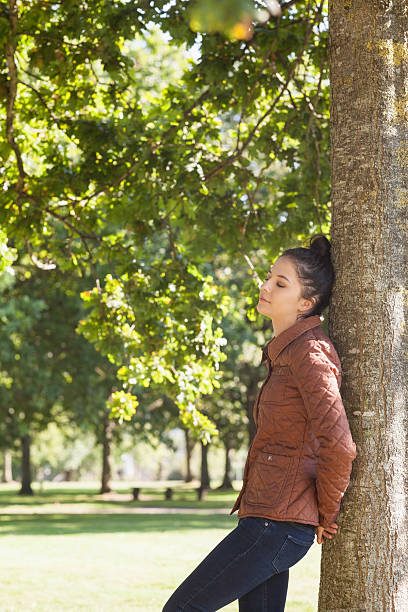 istock Attractive woman leaning against a tree with closed eyes 511094159