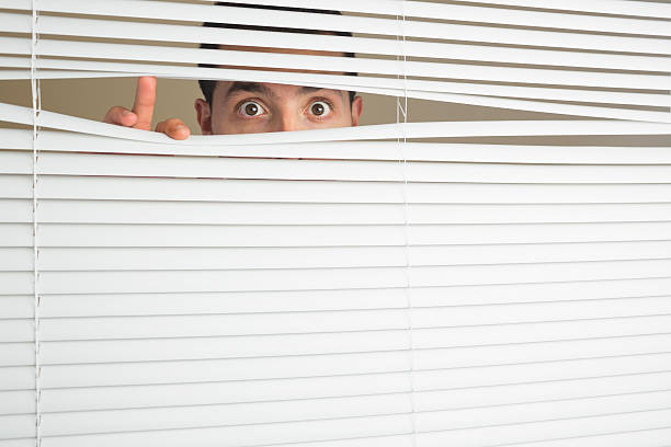 istock Shocked male eyes spying through roller blind 511095151