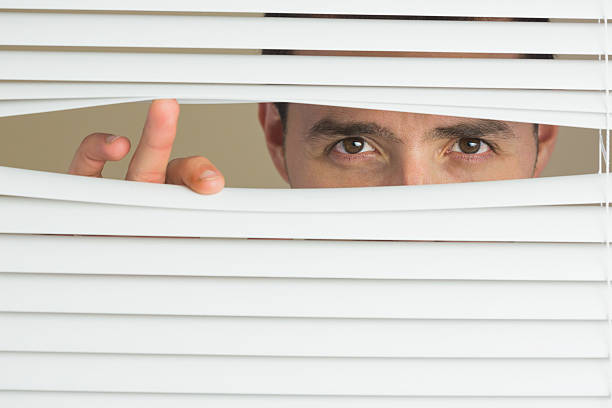 istock Focused male eyes spying through roller blind 511095153