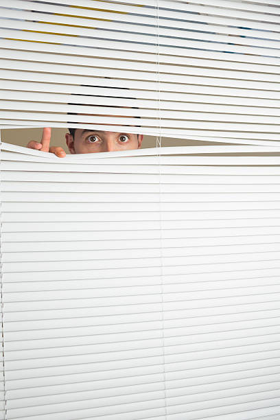 istock Astonished male eyes spying through roller blind 511095157