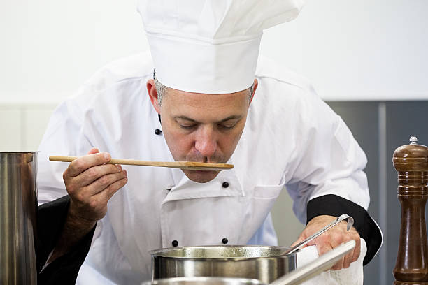 istock Focused head chef tasting sauce with wooden spoon 511095435