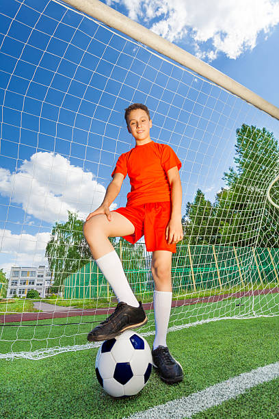 istock Smiling boy in uniform with one leg on football 511096259