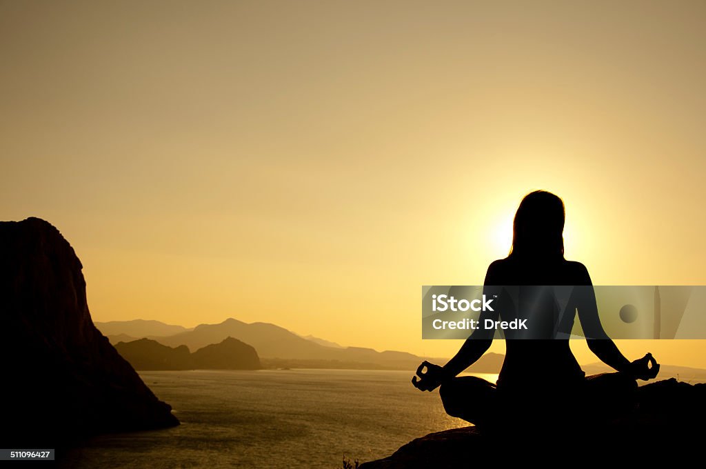 yoga lotus position silhouette at sunrise Young model is doing yoga lotus position on seaside at sunrise Adult Stock Photo