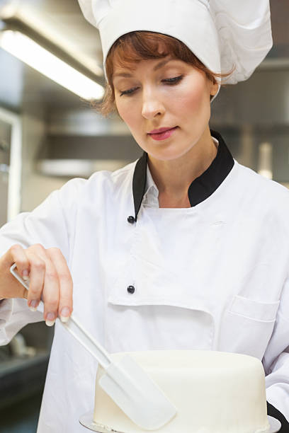 istock Pretty concentrating head chef finishing a cake with icing 511097315