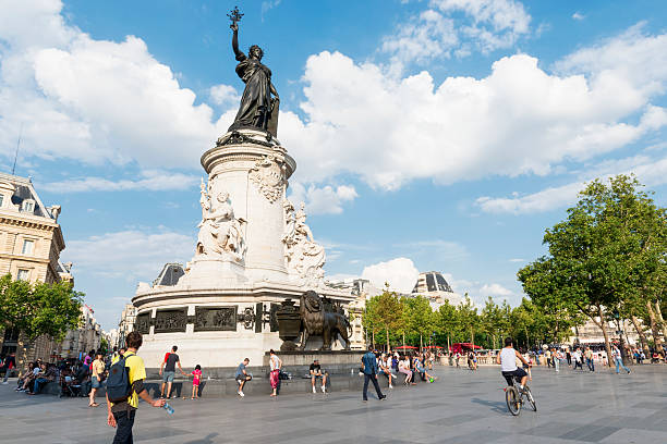 Paris, France - August 1, 2014: Place de la Republique in Paris, France on a sunny summer day. Pedestrians are walking around some people cycling. Republic Square is a famous place in Paris, France. The monument is dedicated to the third republic.
