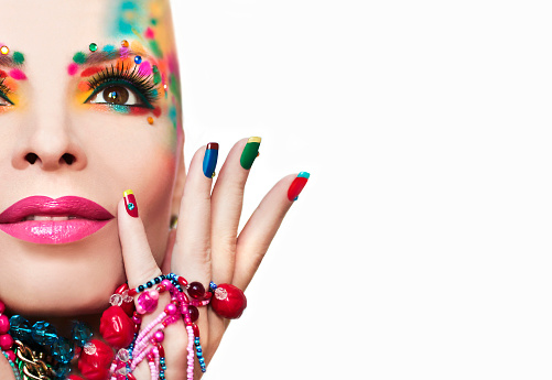 Colorful French manicure and makeup on a girl with rhinestones and decorations on a white background.