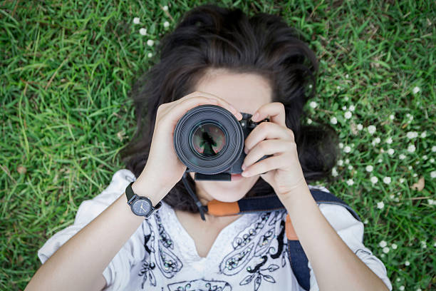istock Young woman lying on grass ground with camera. 511099294