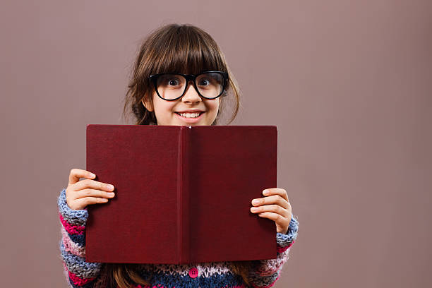 istock Little girl hiding behind book 511106558