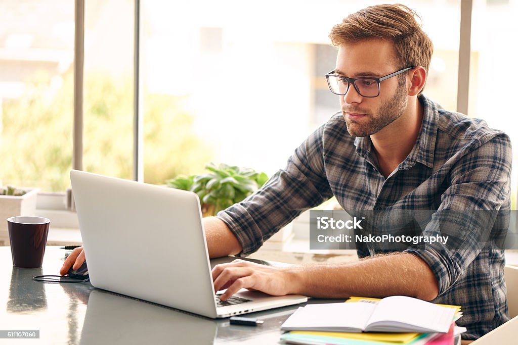 Self employed business person working from home Young man with glasses working on his notebook, with a fresh cup of coffee nice and early in the morning, getting the business out of the way nice and early in the day Men Stock Photo