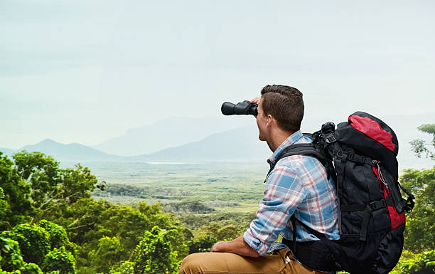 montaña escalador mirando a través de binoculares - pursuit binoculars mountain sky fotografías e imágenes de stock