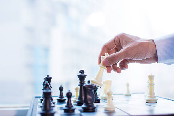 Hand moving the king in chess game stock photo