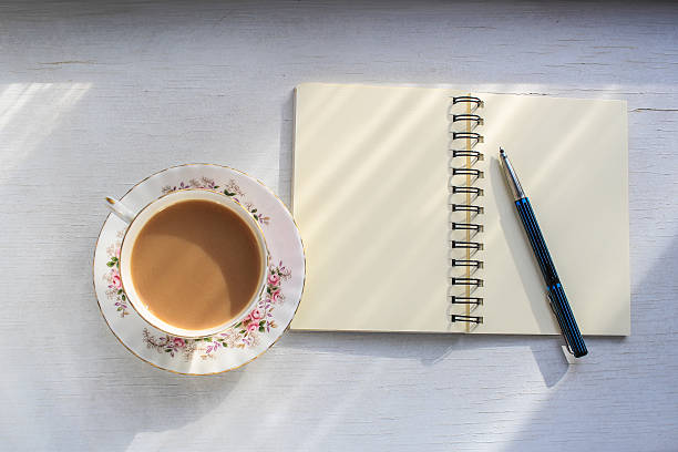 istock Open notebook and cup of tea in sunbeams table top. 511120268
