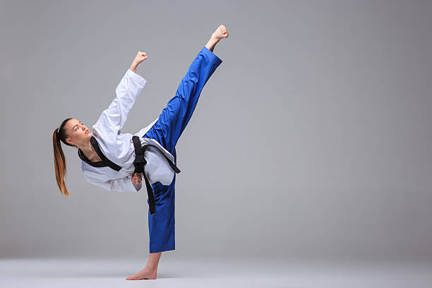 The karate girl with black belt The karate girl in white kimono and black belt training karate over gray background. taekwondo photos stock pictures, royalty-free photos & images