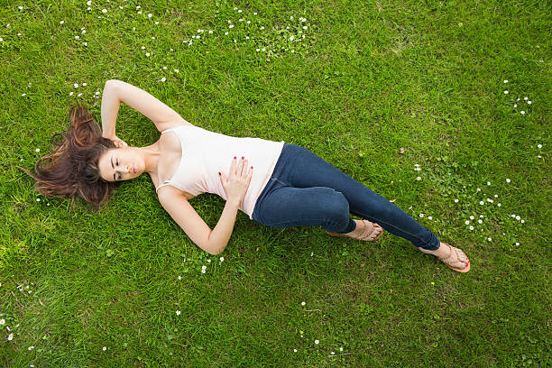 istock Beautiful brunette woman lying on grass 511132387