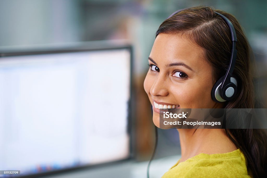 I'm connected and listening Shot of an  attractive female with headsets on smiling while looking over her shoulder at work Call Center Stock Photo
