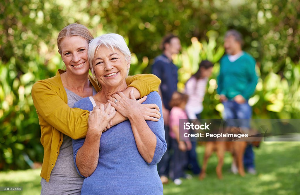 She's the best Portrait of a young woman hugging her mother with the rest of the family in the background Multi-Generation Family Stock Photo