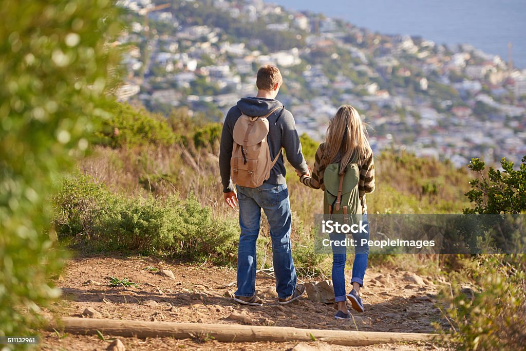 Out on the trail together Rear view shot of a young couple walking down a hiking trail 20-29 Years Stock Photo