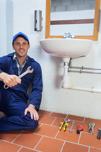 istock Cheerful plumber holding wrench sitting next to sink 511133861