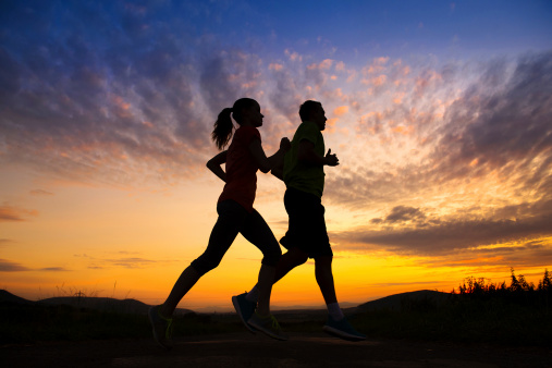 Silhouette of young couple running in sunset