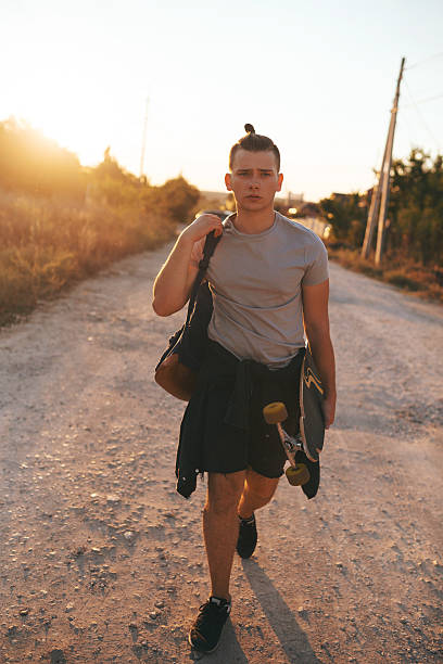 istock Image of a man with longboard going on road 511200876
