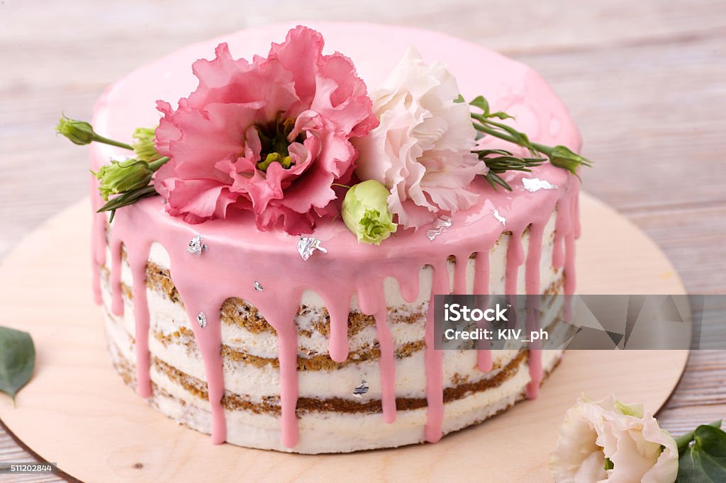 Carrot cake with pink glaze Carrot cake with pink glaze, beautiful flowers and edible silver as a decoration Cake Stock Photo