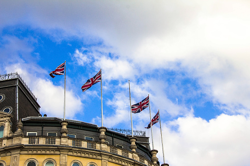 British flags waving in the wind at the roof of building on Trafalgar square. London, UK
