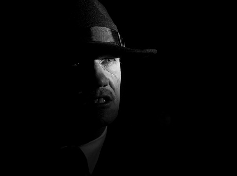 Scar face. Vintage portrait of a senior man in black suit,  holding a gun. Cold and dangerous expression,