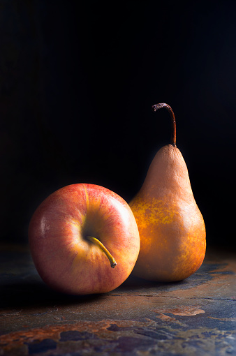 Whole green, yellow and red apples on the glass fruit bowl on a gray background