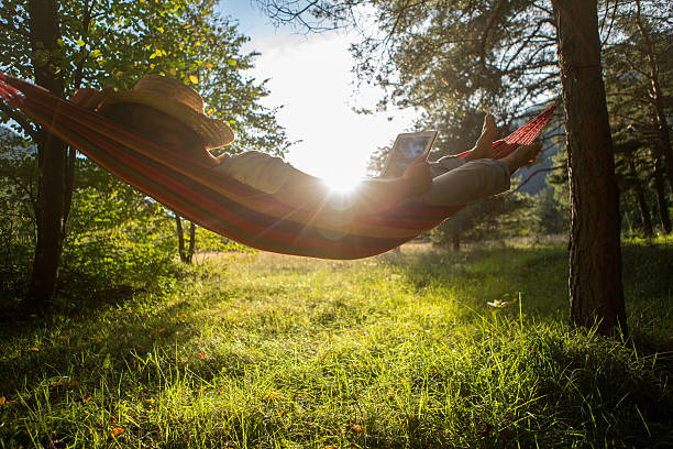 Man on hammock with digital tablet http://www.mediafire.com/convkey/6d6b/7mean2vh9anb8s3fg.jpg hammock men lying down digital tablet stock pictures, royalty-free photos & images