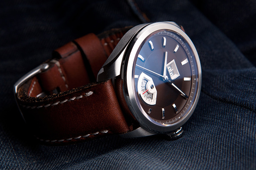 Wrist watch on leather strap on jeans background