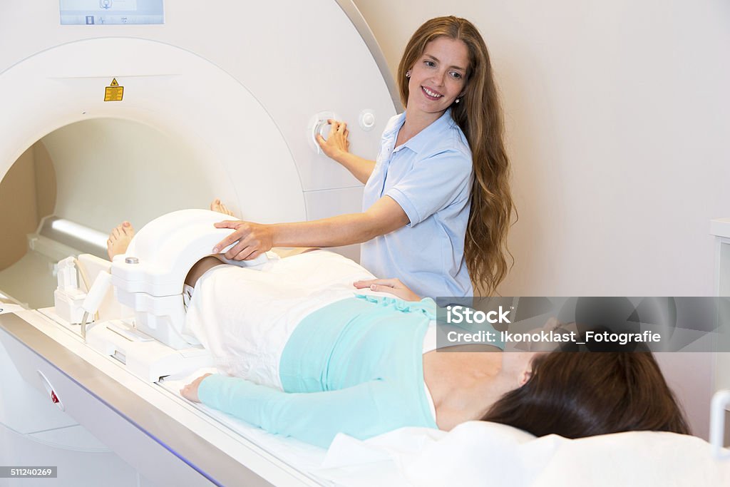 Medical technical assistant preparing scan of knee with MRI Medical technical assistant councelling patient and preparing scan of the knee with magnetic resonance tomography MRI in radiology MRI Scan Stock Photo