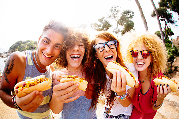 Friends Eating Hotdogs Friends enjoying having hotdogs together fish eye effect stock pictures, royalty-free photos & images