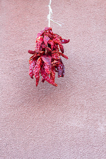 A red chili pepper ristra hanging against an adobe wall. A ristra hung near one's door is not only decorative in New Mexico but also protects against evil spirits according to traditional beliefs. Lots of copy space at the bottom of the frame.