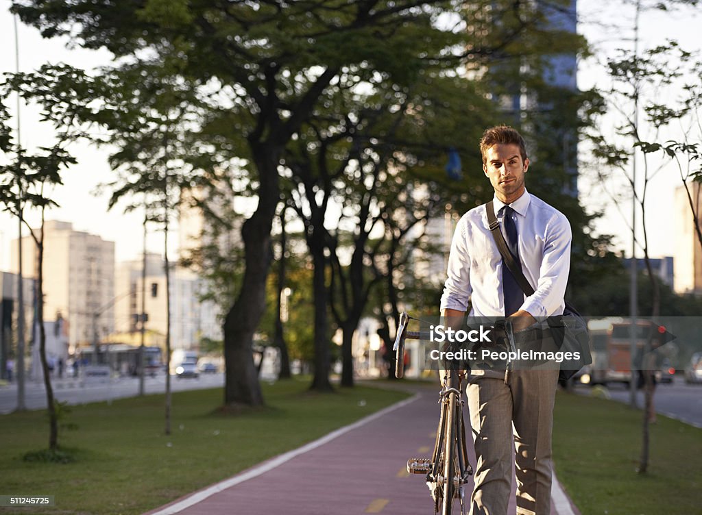 Off on his carbon free commute Shot of an attractive young man pushing his bicycle on the way to work Active Lifestyle Stock Photo