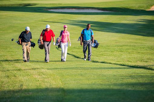 Four golfers talking while walking on the golf course. 